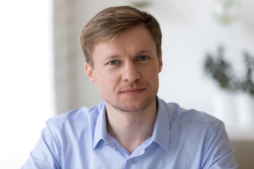 Portrait of a man with short light brown hair in a light blue shirt