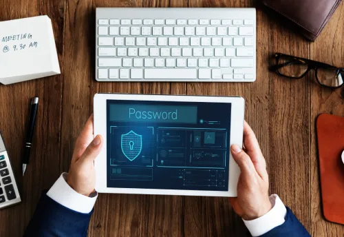 Hands holding a tablet showing a password screen above a keyboard