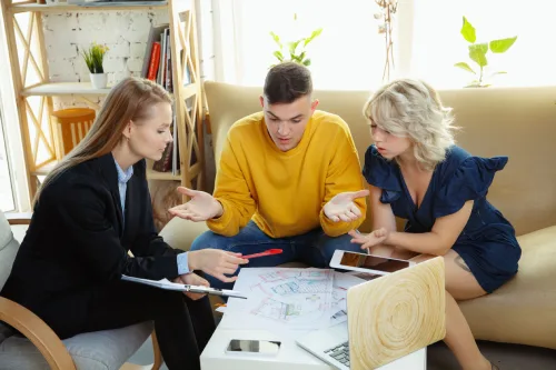 Three people discussing documents around a coffee table