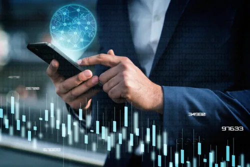 Hand holding a smartphone with a glowing globe and financial chart overlay