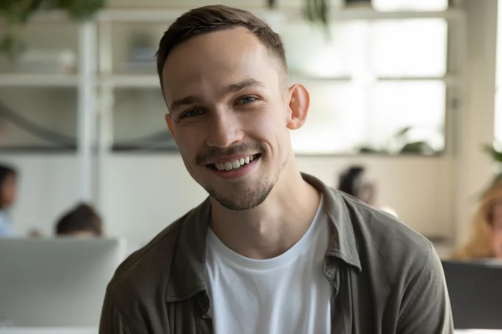 Portrait of a smiling man in an olive jacket over a white t-shirt