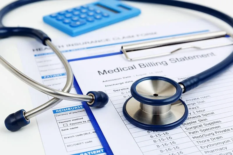 Stethoscope and calculator on a medical billing statement and a health insurance claim form
