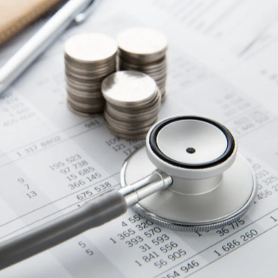 Stethoscope beside stacked coins on a billing statement