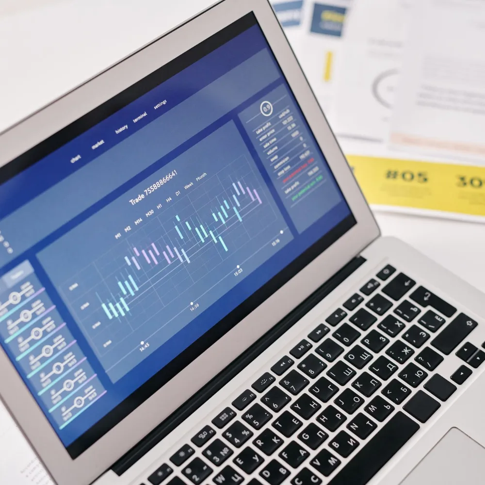Laptop showing revenue charts beside printed reports