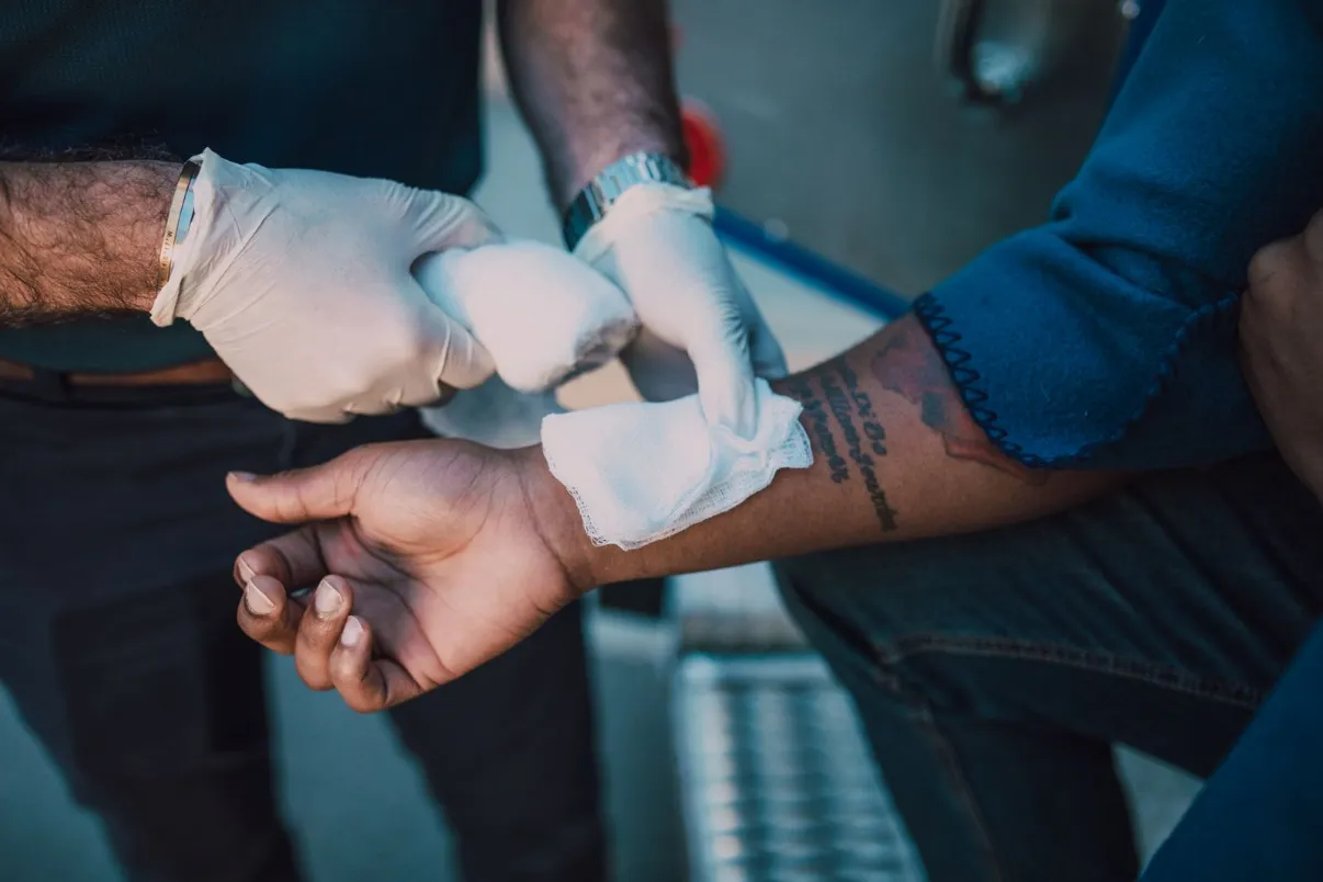 Gloved clinician applying a bandage to a patient's arm